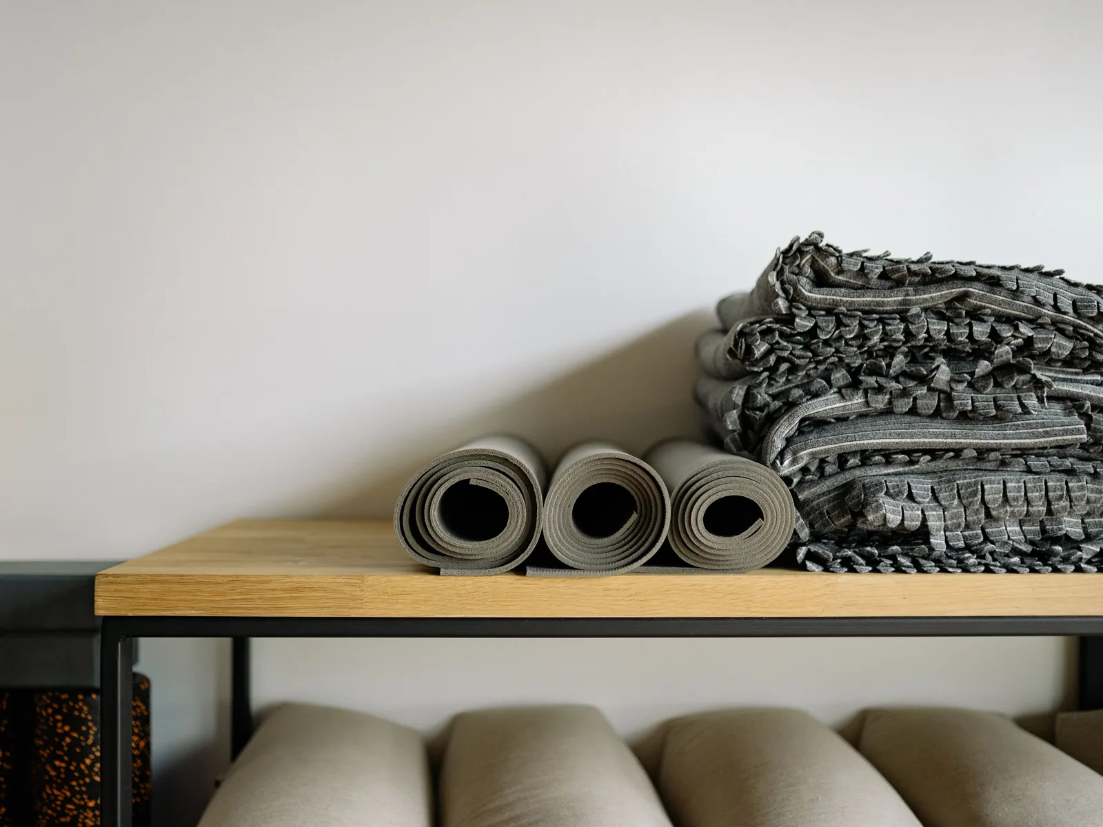 Des tapis et des couvertures de sport enroulés puis rangés sur une étagère.